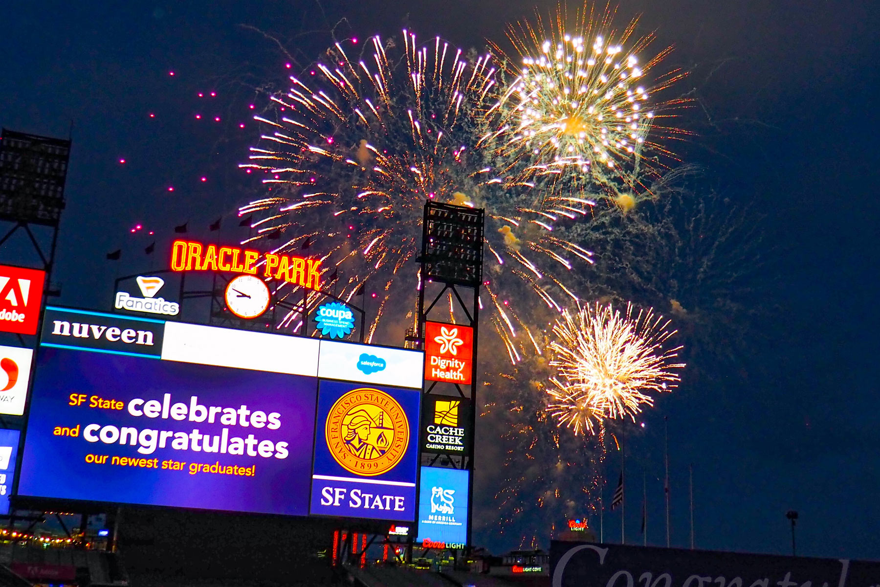 Jumbotron congratulating new graduates with fireworks in the background.