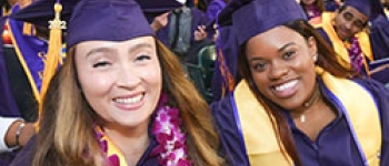 Two womoen dressed in regalia pos for a photo